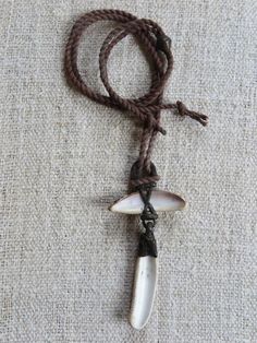 a white and black pendant on a brown cord with a cow's eye charm