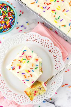 a piece of cake on a white plate with sprinkles next to it