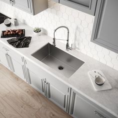 a kitchen sink sitting on top of a counter next to gray cupboards and drawers