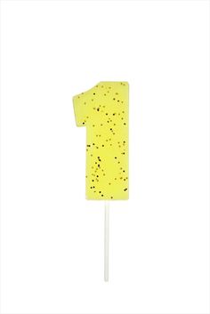 a yellow number one cake on top of a white stick with sprinkles