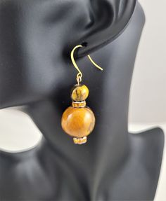 A large and small wooden ball, enameled with glittery paint and black/brown accents.  Between each ball is a lovely topaz colored crystal rondelle, for additional bling. These earrings move nicely and are very light weight. Ear wire is gold plated. Wooden Ball Earrings, Brown Wooden Bead Earrings As A Gift, Brown Wooden Beads Round Jewelry, Brown Earrings With Wooden Beads As Gift, Brown Wooden Beads Jewelry, Brown Round Wooden Beads Jewelry, Brown Dangle Earrings With Large Beads, Unique Brown Earrings With Wooden Beads, Unique Brown Wooden Beads Earrings