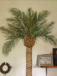 a palm tree painted on the wall next to a shelf with a wreath and plaque