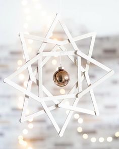 a white star ornament hanging from a string with lights in the back ground