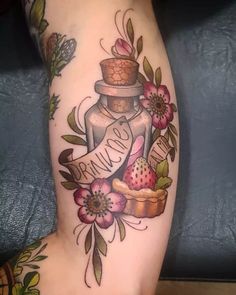 a tattoo on the leg of a woman with flowers and an empty jar in it