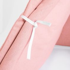 a pink pillow with a white ribbon tied around it