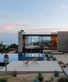 a modern house with a pool in the middle and an outdoor dining area next to it