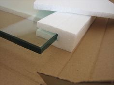 two pieces of white foam sitting on top of a cardboard box