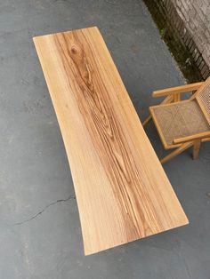 a wooden table sitting on top of a cement floor next to a chair and side table