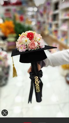 someone is holding a graduation hat with flowers on it in the middle of a store aisle