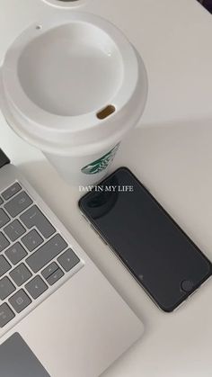 an open laptop computer sitting on top of a white desk next to a cup of coffee