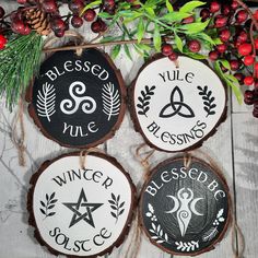 three wood slices with the names of four different businesses hanging from strings next to berries and pine cones