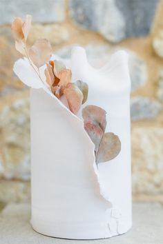 a white vase with dried flowers in it