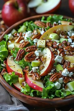 a salad with apples, cheese and pecans in a wooden bowl on a table