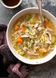 a bowl of chicken noodle soup next to a cup of tea