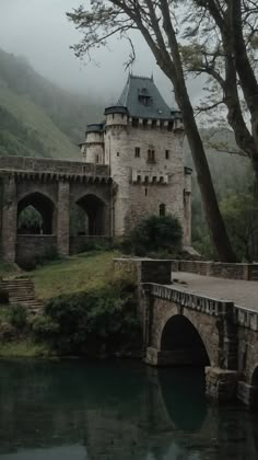 an old castle sitting on top of a hill next to a river