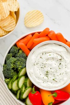 a bowl filled with veggies and dip surrounded by chips