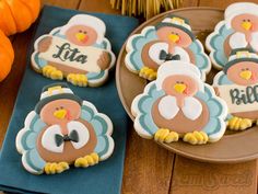 decorated cookies with turkeys and name tags on them are sitting on blue napkins next to an orange pumpkin