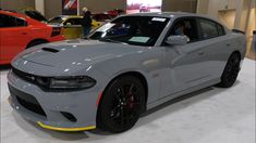 a gray dodge charger parked in a showroom next to other cars on display