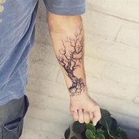 a man with a tree tattoo on his arm is holding onto a potted plant