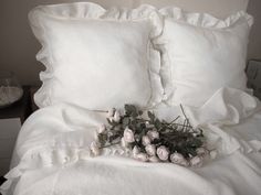 a bunch of flowers that are on top of a white bedding with ruffles