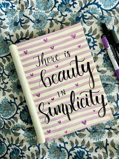 there is beauty in simplatity written on a notepad next to some pens