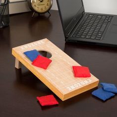 a wooden board game sitting on top of a desk next to a laptop and clock