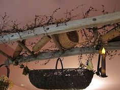 a wicker basket hanging from the ceiling next to a lit candle and some branches