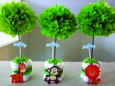 four small cupcakes with green paper flowers and animals on them, sitting on a table