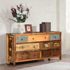 a vase with flowers on top of a wooden dresser next to a book shelf filled with books