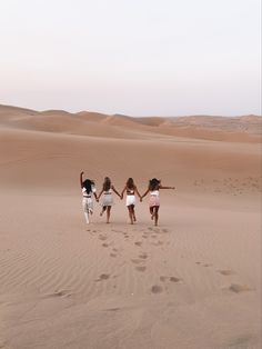 three girls walking in the desert holding hands