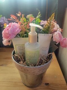 a wooden table topped with a bucket filled with lots of flowers and personal care items