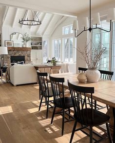 a dining room table with black chairs and a white couch in front of a fireplace