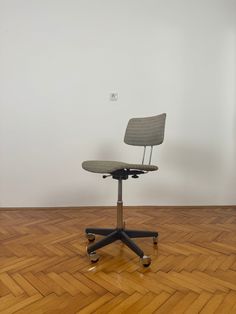 an office chair sitting on top of a hard wood floor next to a white wall