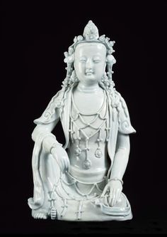 a white buddha statue sitting on top of a black surface