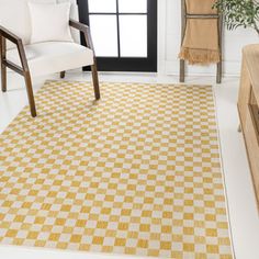 a yellow and white checkered area rug in a living room with a chair, coffee table and window