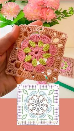 a hand holding up a crocheted square with flowers in the background