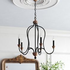 a white chandelier hanging from the ceiling in a room with a mirror and potted plant