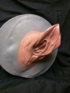 a white hat with a pink substance on it's brim sits on a black cloth