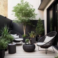 an outdoor living area with black and white furniture, potted plants and large windows