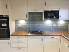 a kitchen with white cabinets and wood counter tops, an oven and microwave above the stove