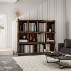 a living room filled with furniture and bookshelves next to a stair case on the wall