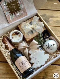 an open gift box with wine, cookies and other holiday treats in it on a wooden table