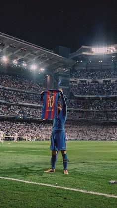 a soccer player is holding up his shirt in the air at a stadium full of people