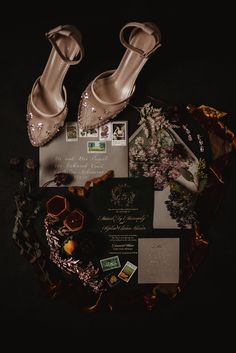 wedding shoes and stationery laid out on top of each other in the middle of a black background