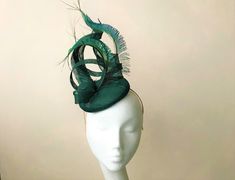 A burst of peacock feathers adorns this sculptural sinamay detail headpiece, fixed to an emerald pillbox  base.  Perfect finishing touch for any wedding or Royal Ascot outfit (meets Royal Enclosure size regulations).   The disc is approx 16 cm in diameter Secured with elastic or a satin covered hairband in a choice of colours to blend your hair colour. I recommend elastic with this shape.   Each piece is handmade by me for you, using the highest quality materials which takes about 5 days, if you have a specific date you need the headpiece please get in touch and I will ensure you receive in good time. If you would like the piece to be made to match your outfit, or adapted please contact me (a swatch can be sent or matched to your required colour) Presented in a branded hat box.  Please che Elegant Green Feathered Headpieces, Green Wedding Fascinator With Feathers, Green Feathered Headpiece For Weddings, Fitted Green Hat With Feathers, Royal Ascot Outfit, Ascot Outfits, Ascot Ladies Day, Emerald Green Wedding, Emerald Green Weddings