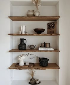 the shelves are filled with vases, books and other decorative items in white painted walls