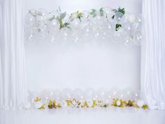 white flowers and greenery are arranged on the wall