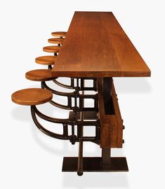 a long wooden table with six stools on each side and an open drawer in the middle