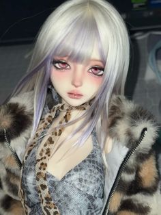 a close up of a doll with white hair and blue eyes wearing a fur coat