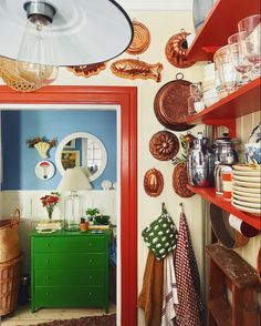 a kitchen with red shelves and green cabinets